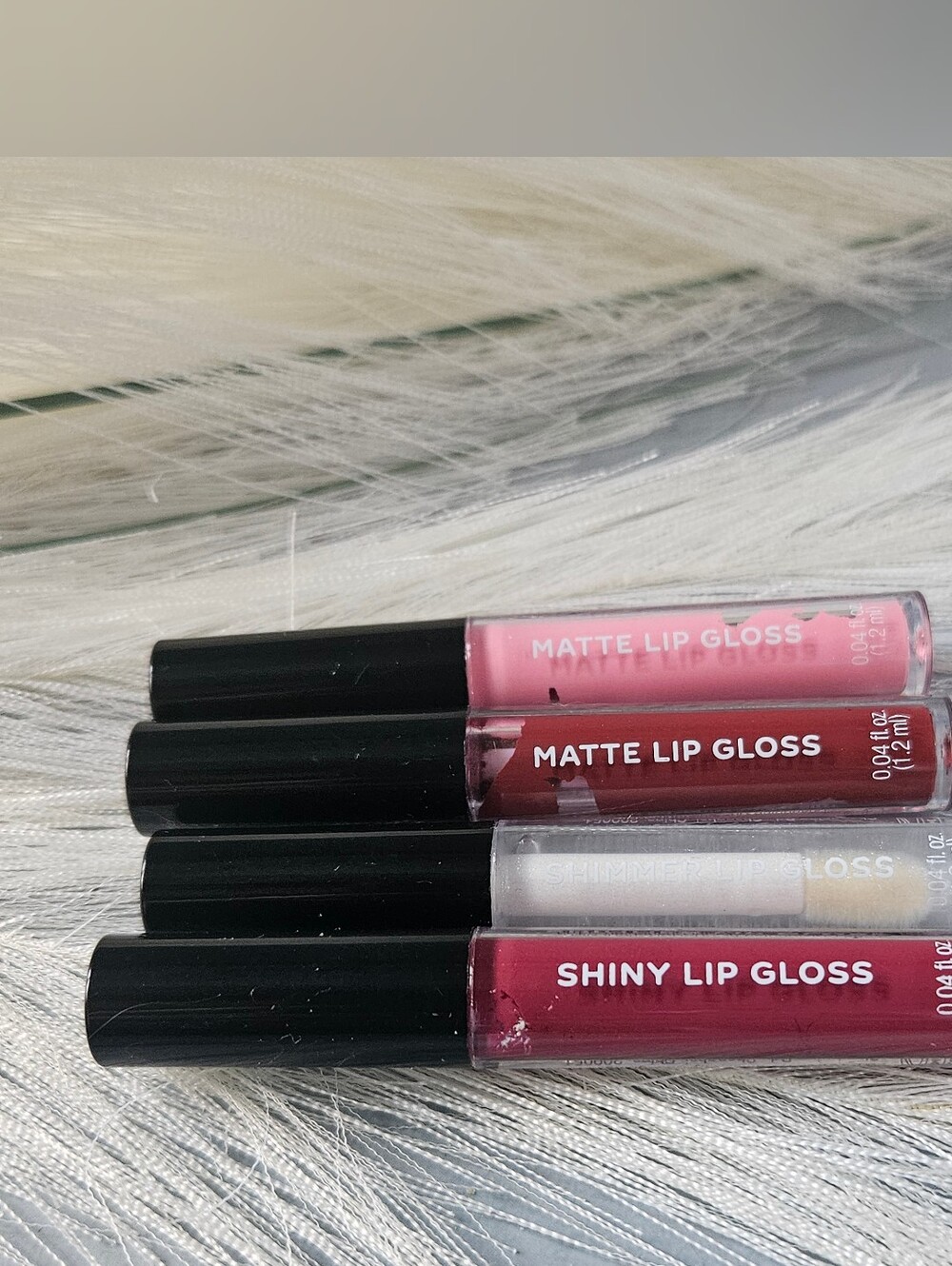 Four miniature lip gloss tubes, each containing 0.04 fl. oz. (1.2 ml) of product